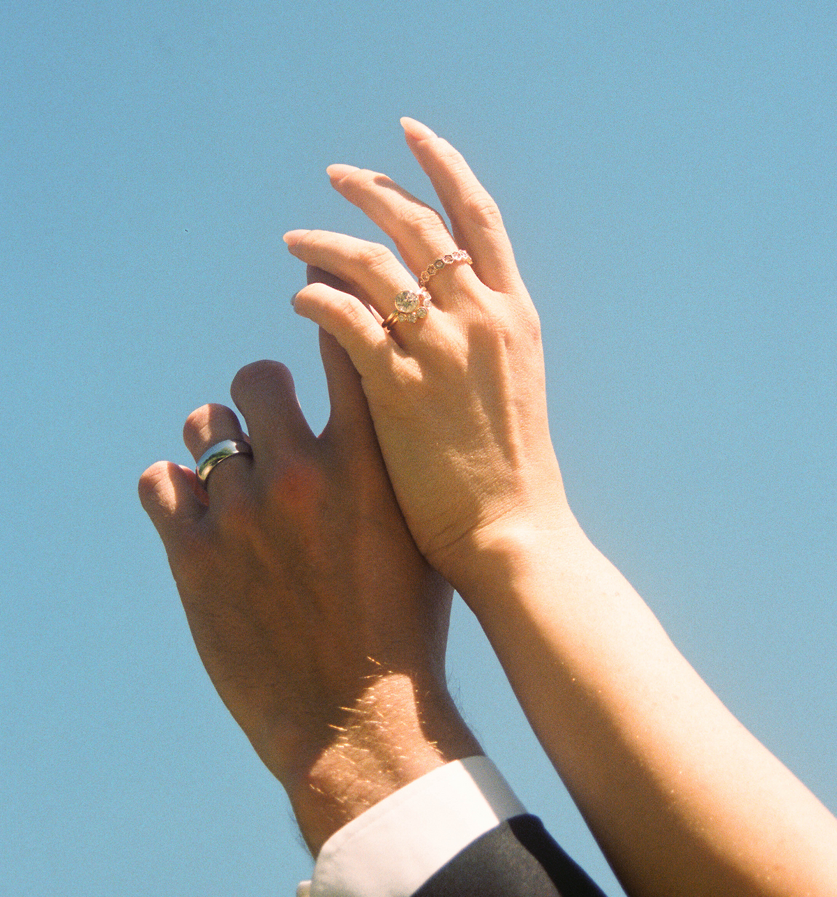 Image of A Couple Holding Their Hands Up With Custom Engagement Rings And Wedding Bands